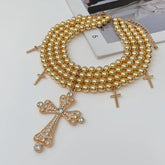 Gold beaded necklace with cross pendants on a white surface